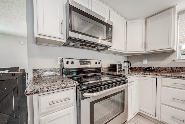 kitchen with stainless steel appliances, dark stone counters, and white cabinets