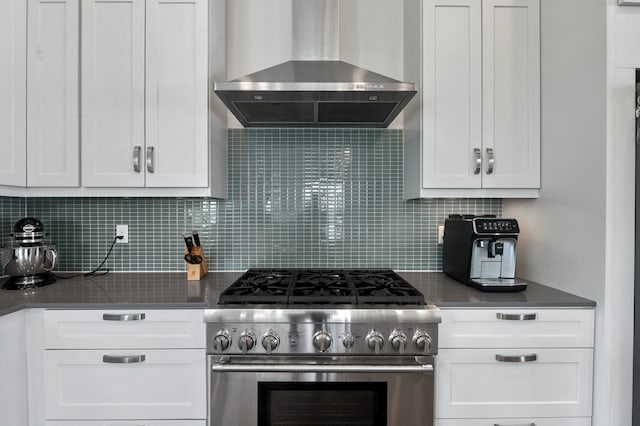 kitchen with white cabinetry, high end stainless steel range, wall chimney range hood, and backsplash