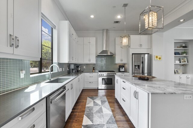 kitchen with white cabinetry, sink, appliances with stainless steel finishes, wall chimney exhaust hood, and a center island