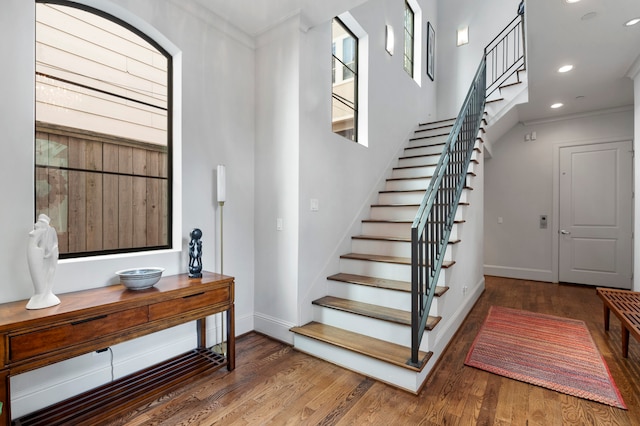 staircase featuring wood-type flooring and crown molding