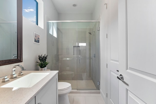 bathroom featuring a shower with door, vanity, toilet, and tile patterned floors