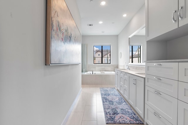 bathroom with tile patterned flooring, vanity, and tiled tub