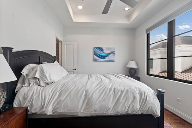 bedroom with a raised ceiling, ceiling fan, and dark hardwood / wood-style floors