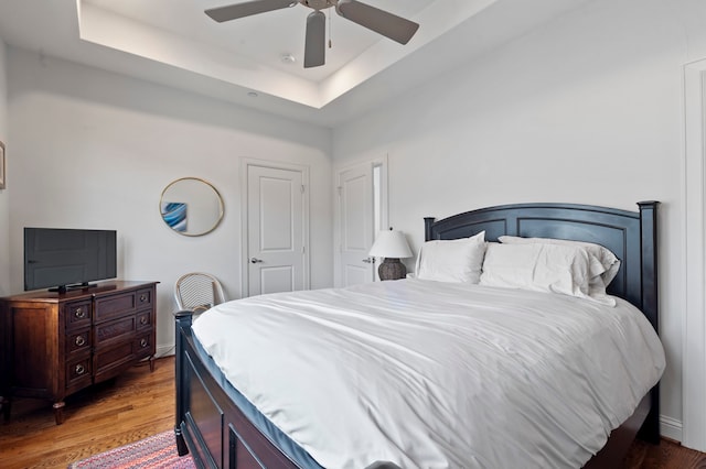 bedroom featuring hardwood / wood-style flooring, ceiling fan, and a tray ceiling