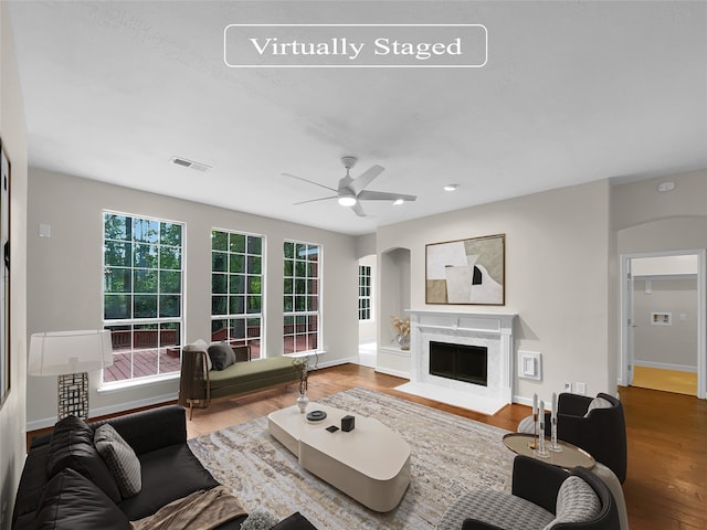 living room featuring ceiling fan, a high end fireplace, a healthy amount of sunlight, and hardwood / wood-style flooring