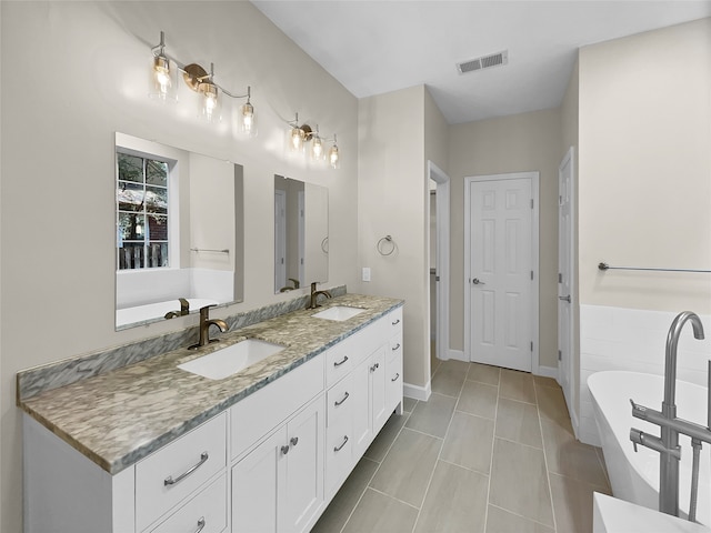 bathroom with tile patterned flooring, vanity, and tiled bath