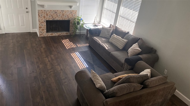 living room featuring a stone fireplace and dark hardwood / wood-style floors