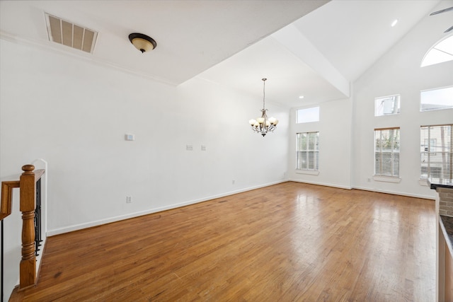 unfurnished living room featuring high vaulted ceiling, wood-type flooring, and a chandelier