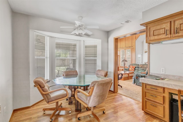 dining room with ceiling fan, light hardwood / wood-style floors, and a textured ceiling