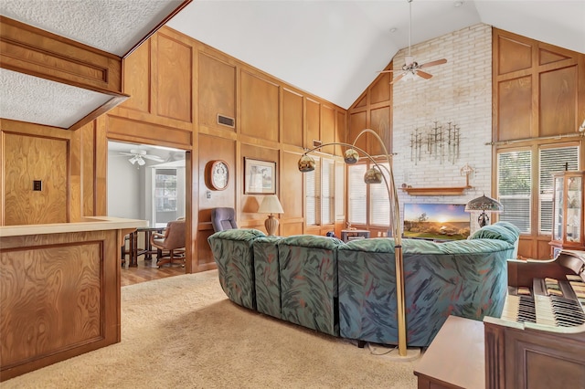 living room with ceiling fan, light colored carpet, high vaulted ceiling, and wood walls