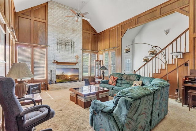 carpeted living room featuring a brick fireplace, wooden walls, high vaulted ceiling, and ceiling fan