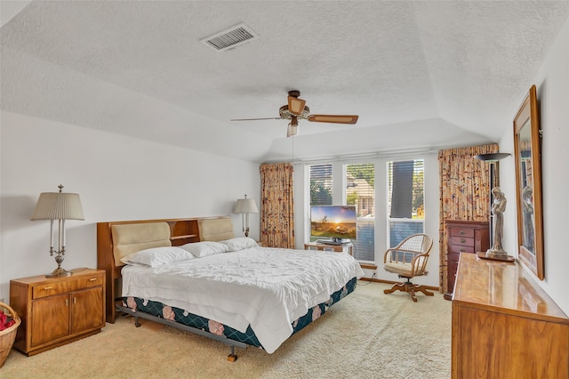 bedroom featuring ceiling fan, vaulted ceiling, light carpet, and a textured ceiling