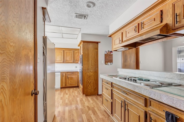 kitchen featuring light hardwood / wood-style floors, a textured ceiling, and appliances with stainless steel finishes