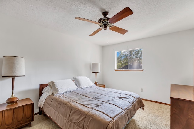 bedroom with ceiling fan, light carpet, and a textured ceiling