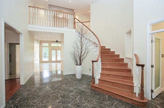 stairway with a towering ceiling and ceiling fan