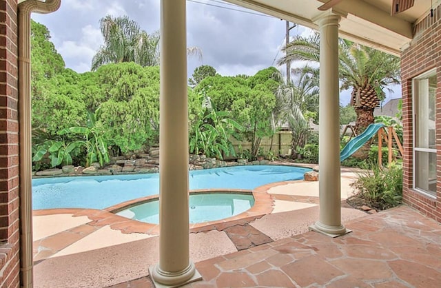 view of swimming pool featuring a playground, an in ground hot tub, and a patio