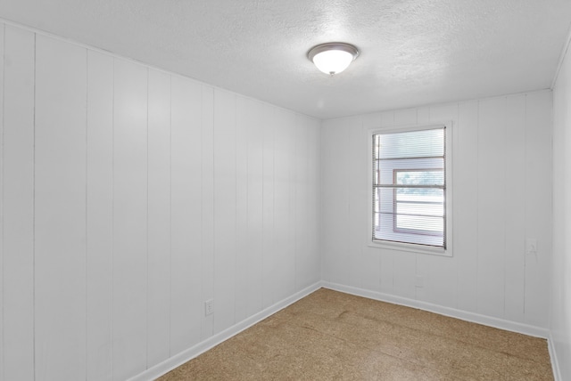 empty room with carpet, a textured ceiling, and baseboards