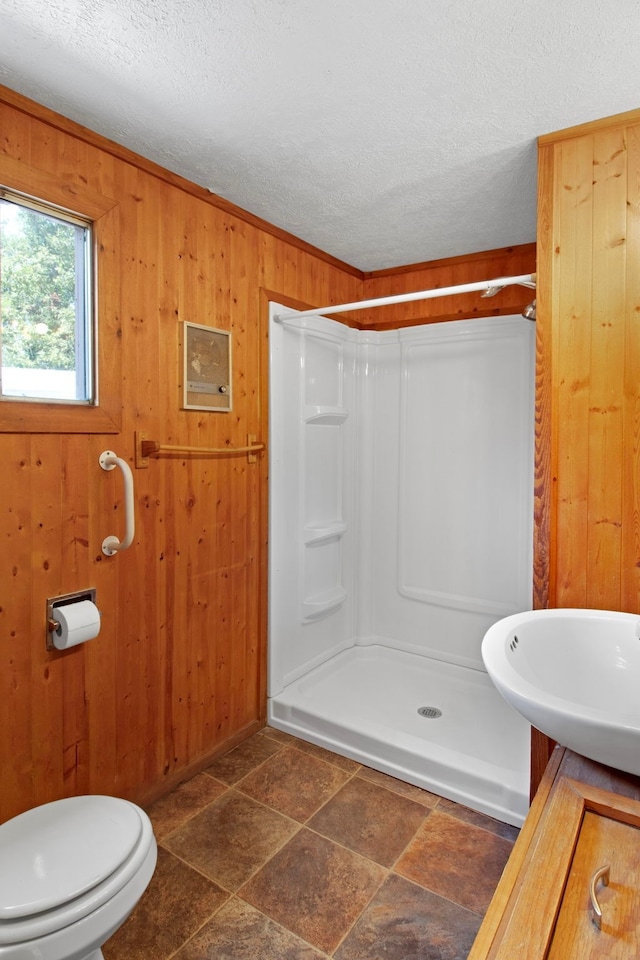 bathroom featuring wood walls, a textured ceiling, and a walk in shower