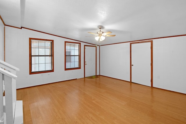 unfurnished room with light wood-style floors, ornamental molding, vaulted ceiling, and a ceiling fan