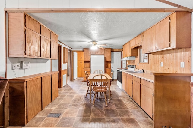 kitchen with a ceiling fan, electric stove, freestanding refrigerator, a textured ceiling, and under cabinet range hood