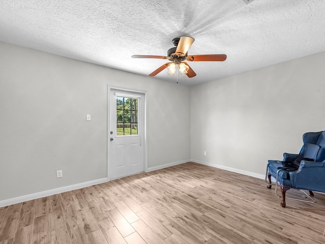 unfurnished room with ceiling fan, light wood-type flooring, and a textured ceiling