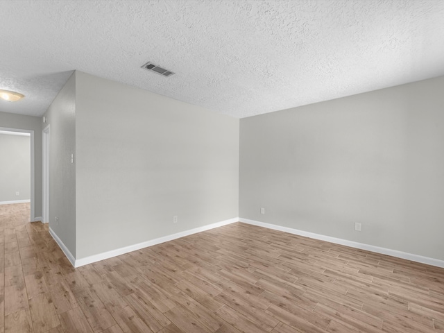 unfurnished room with a textured ceiling and light wood-type flooring