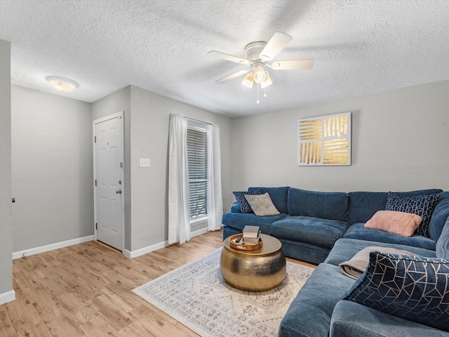 living room featuring light hardwood / wood-style floors, ceiling fan, and a textured ceiling