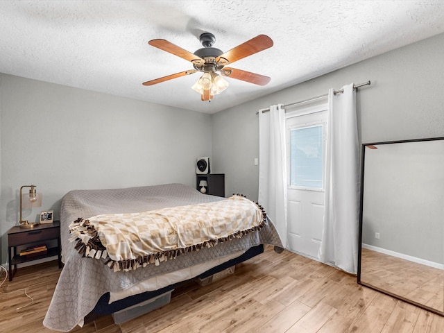 bedroom featuring ceiling fan, light wood-type flooring, and a textured ceiling