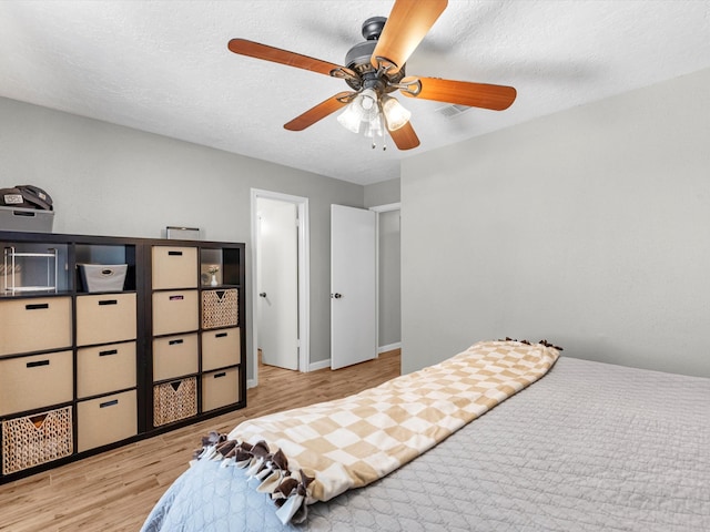 bedroom with ceiling fan, light wood-type flooring, and a textured ceiling