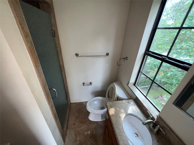 bathroom with tile patterned flooring, vanity, a healthy amount of sunlight, and toilet