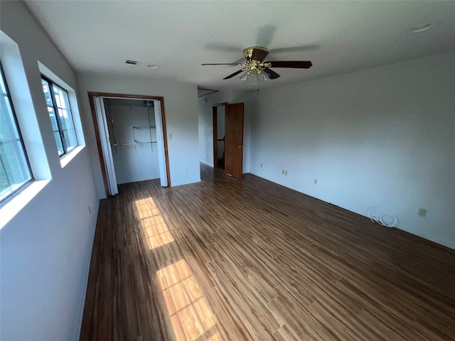 unfurnished bedroom featuring a closet, ceiling fan, multiple windows, and wood-type flooring