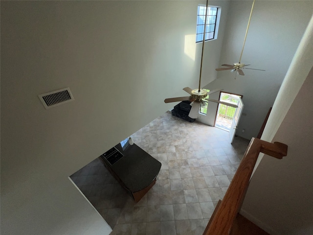 interior space featuring ceiling fan, tile patterned flooring, and a high ceiling