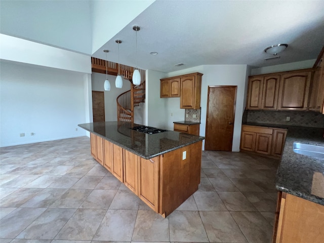 kitchen featuring pendant lighting, decorative backsplash, light tile patterned floors, and dark stone countertops