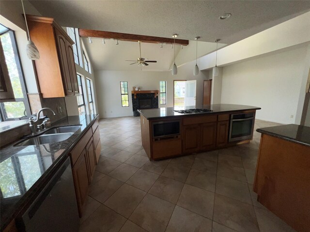 kitchen with vaulted ceiling with beams, a center island, sink, dark tile patterned flooring, and stainless steel appliances