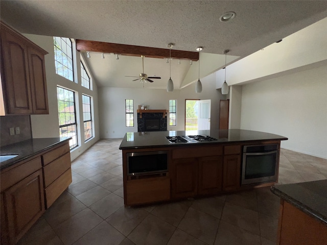 kitchen featuring vaulted ceiling with beams, dark tile patterned flooring, appliances with stainless steel finishes, and ceiling fan