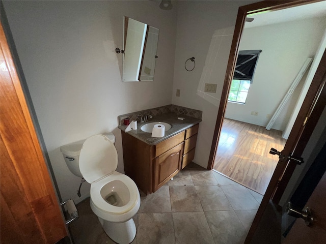 bathroom featuring wood-type flooring, toilet, and vanity