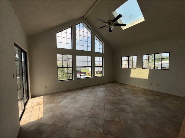 spare room with light tile patterned floors, high vaulted ceiling, a skylight, and ceiling fan