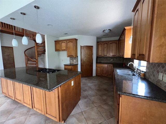 kitchen featuring sink, decorative light fixtures, tasteful backsplash, stainless steel gas cooktop, and light tile patterned floors