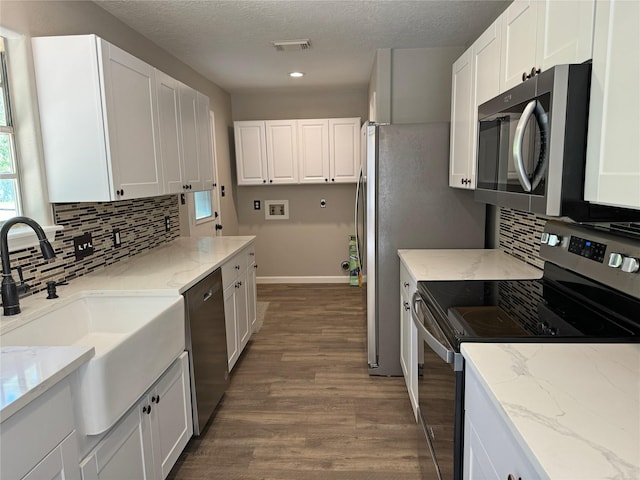 kitchen with white cabinetry, sink, light stone countertops, dark hardwood / wood-style flooring, and appliances with stainless steel finishes