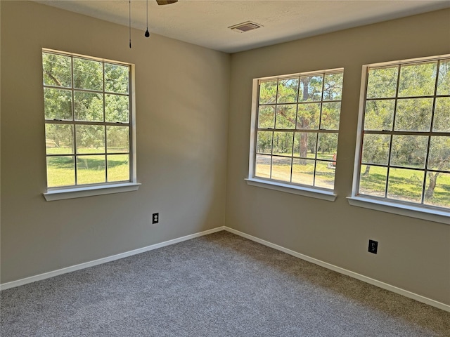 carpeted spare room featuring ceiling fan and plenty of natural light