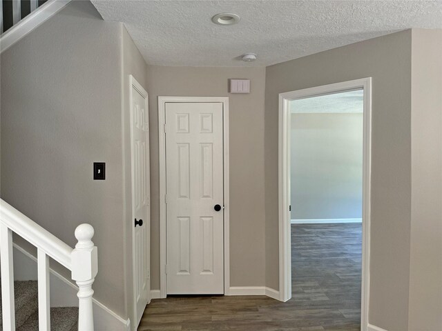 hallway with dark hardwood / wood-style flooring and a textured ceiling