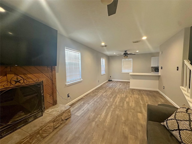 living room with a fireplace, light hardwood / wood-style flooring, and ceiling fan