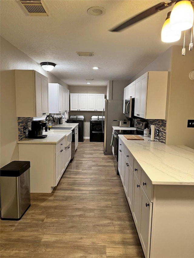 kitchen with backsplash, white cabinetry, stainless steel appliances, and hardwood / wood-style flooring