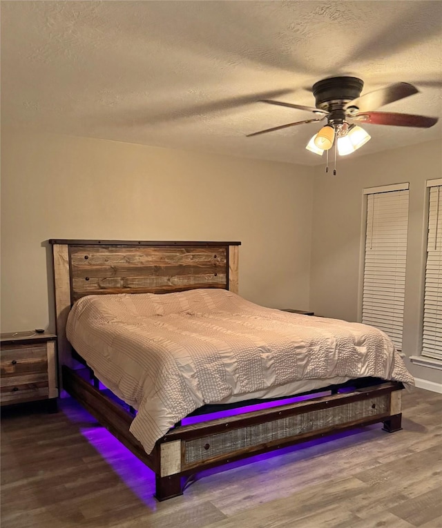 bedroom with ceiling fan, hardwood / wood-style floors, and a textured ceiling