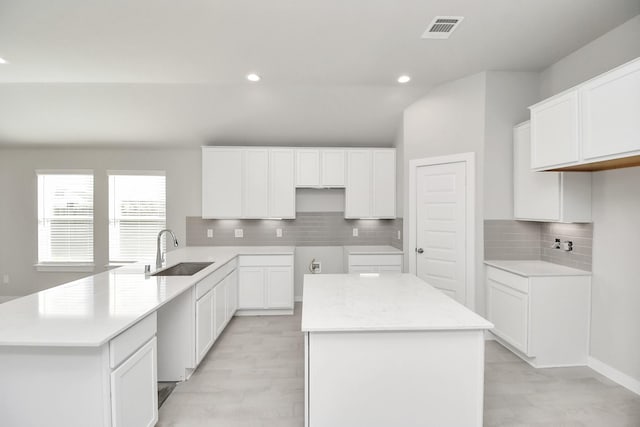 kitchen featuring white cabinetry, sink, a center island, tasteful backsplash, and lofted ceiling