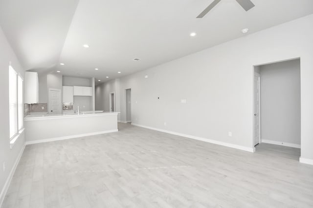 unfurnished living room featuring a wealth of natural light, ceiling fan, and light hardwood / wood-style floors