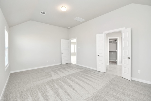 unfurnished room featuring lofted ceiling and light carpet