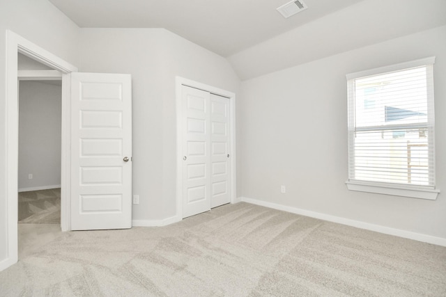 unfurnished bedroom with light carpet, a closet, and lofted ceiling