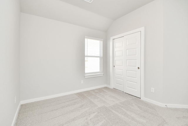 carpeted empty room featuring lofted ceiling