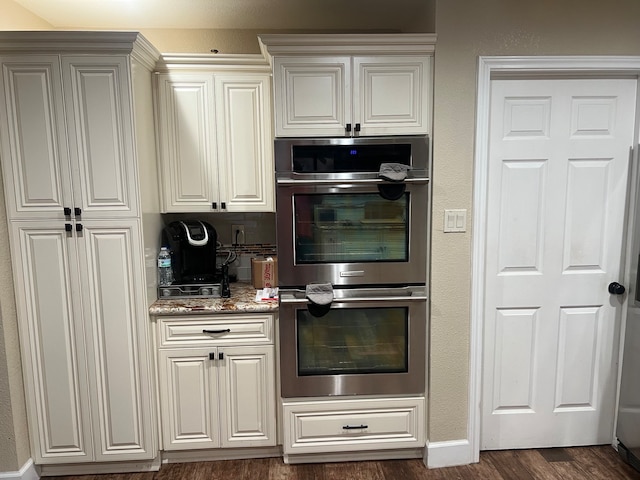 kitchen featuring dark hardwood / wood-style flooring, stone countertops, and double oven